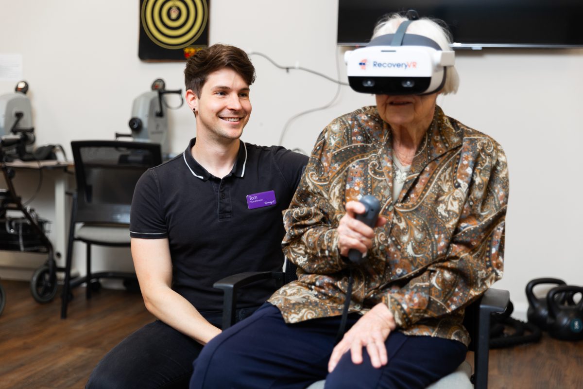 Warrigal Quenbeyan resident Eunice Campbell using the VR headsets under the supervision of Tom McGill. 