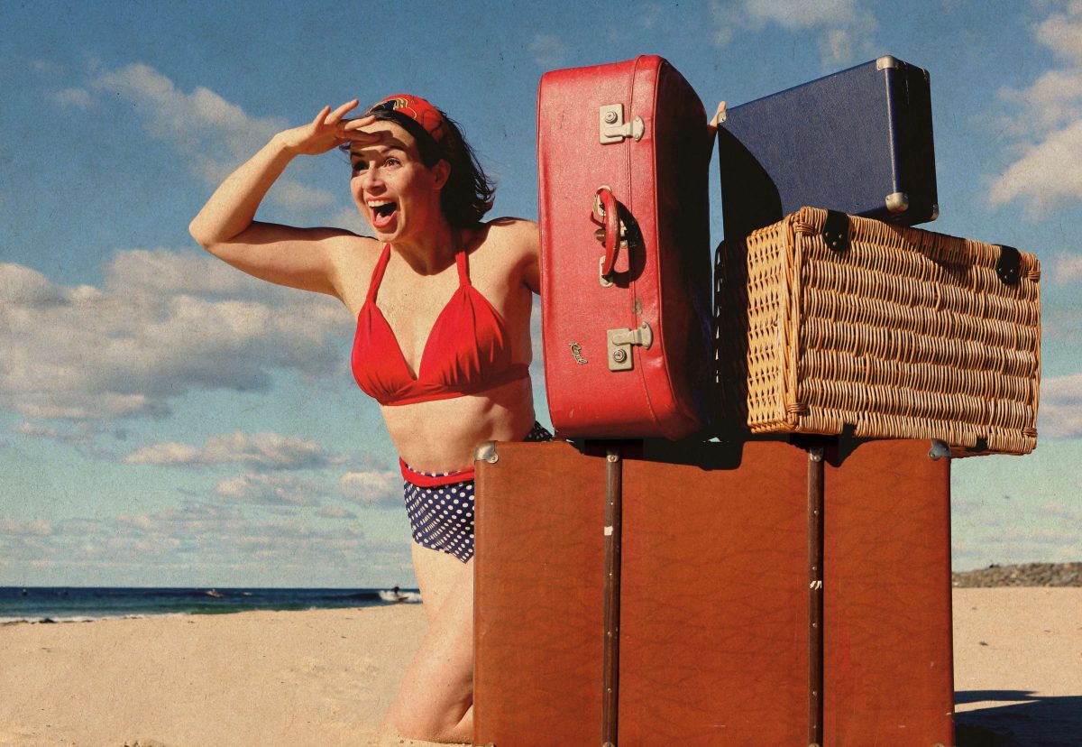 Woman on beach with suitcases from a theatre production