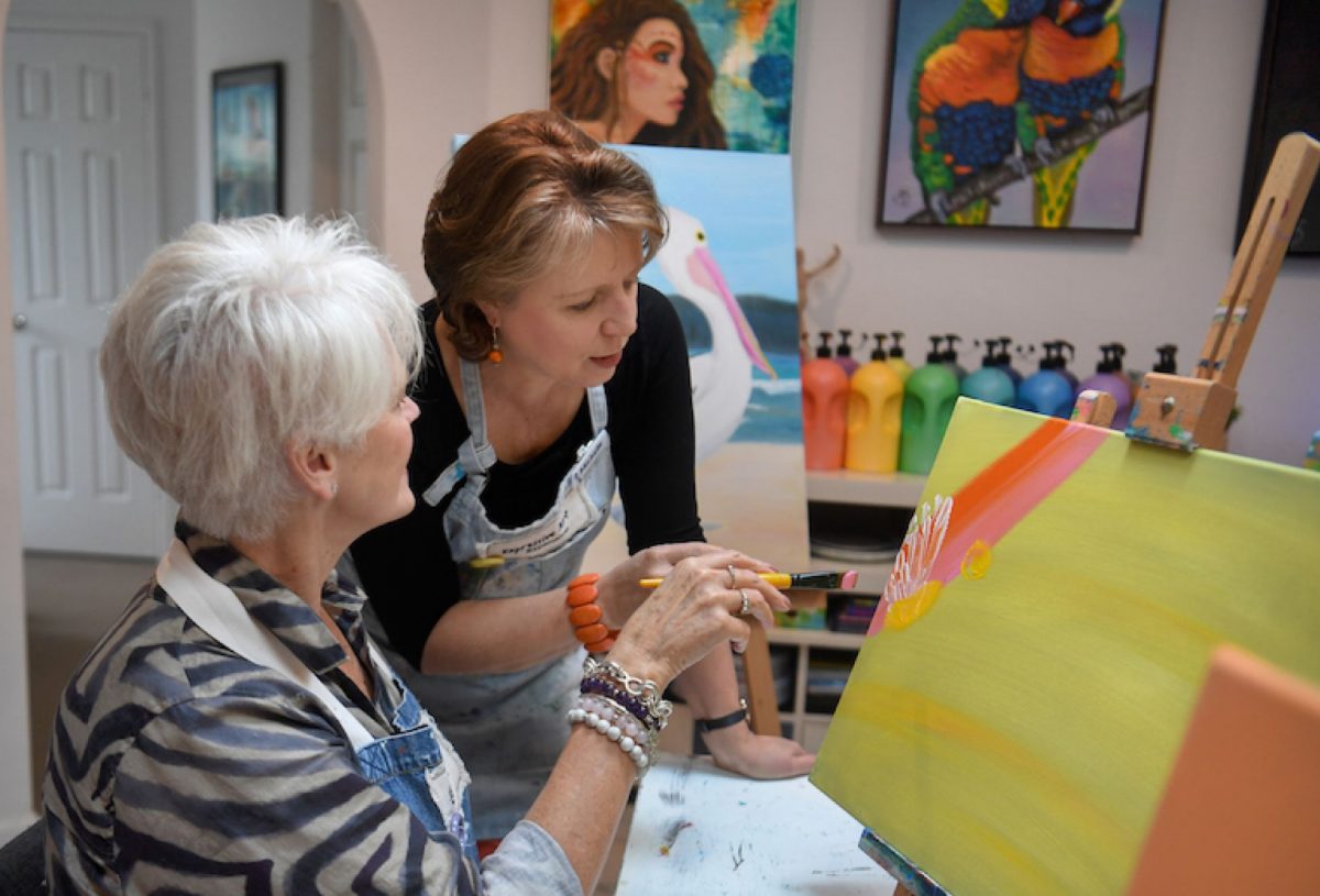Michelle Springett talks to a woman while she paints