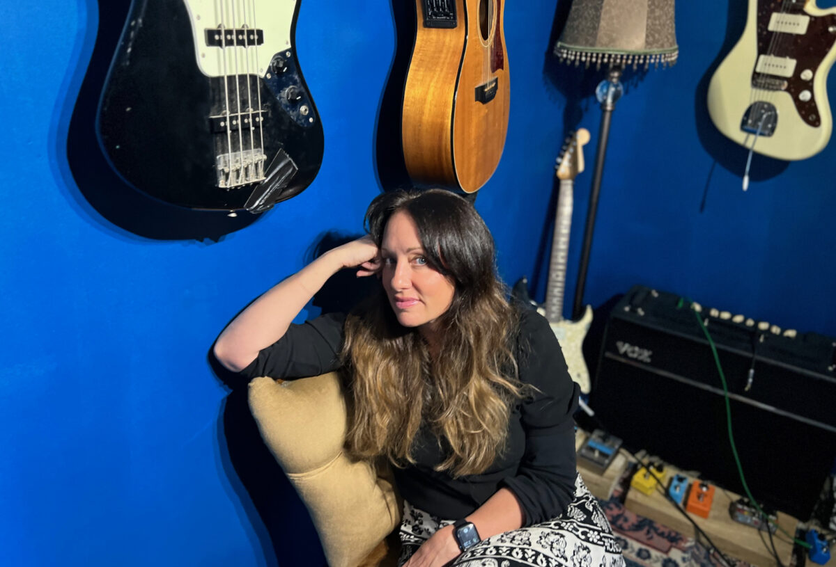 Shelley in a studio with guitars on the walls