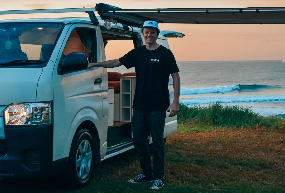Max standing next to a van by the water