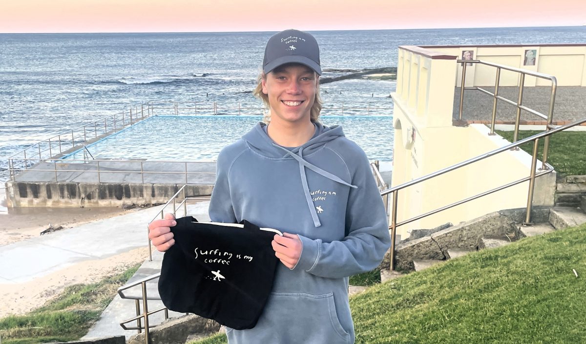 Cooper Palmer at Woonona Beach with "Surfing is my Coffee" hat, jumper and bag.
