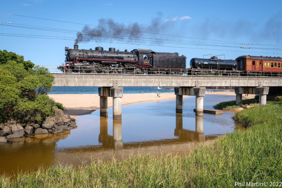 Black steam engine makes its way over a bridge