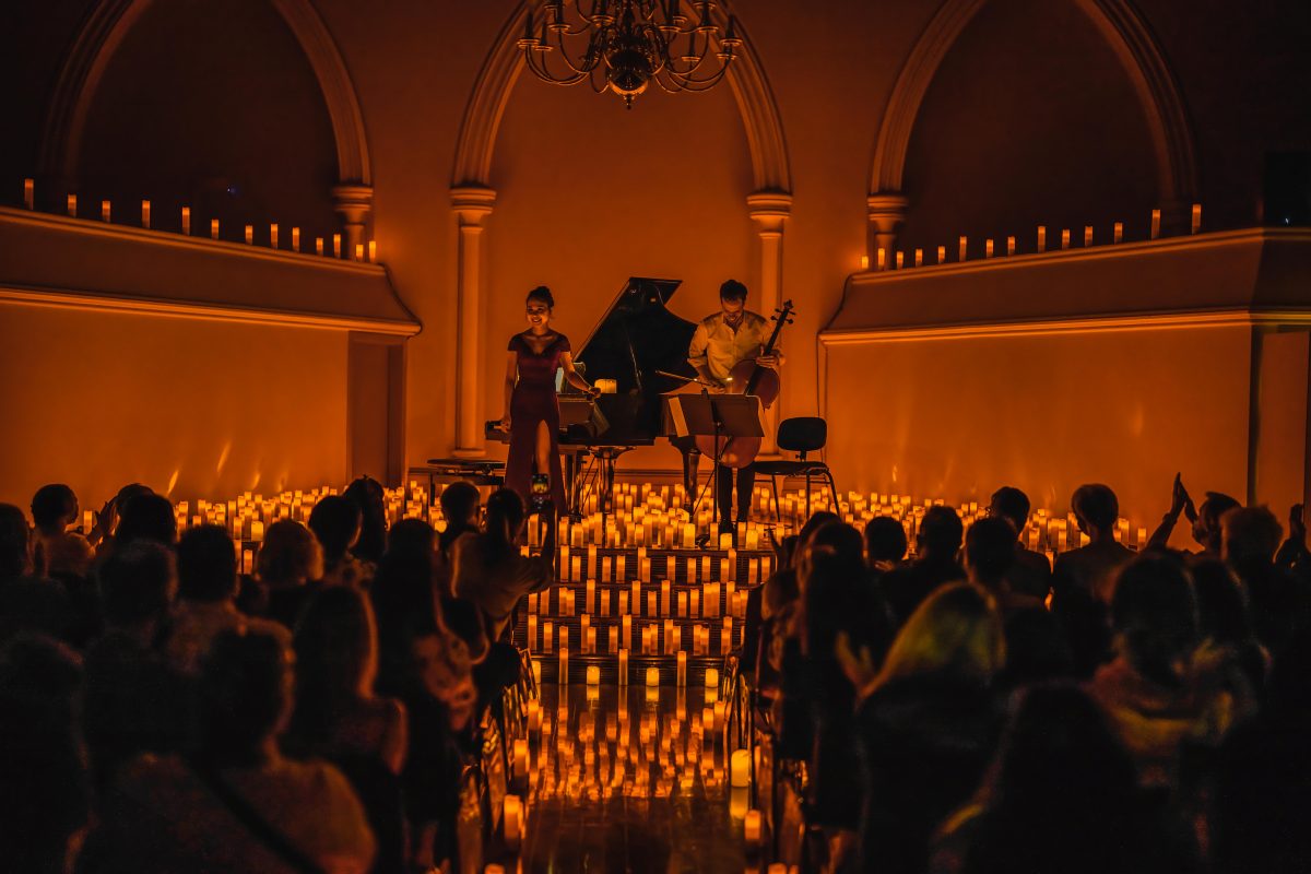 Classical musicians on a stage surrounded by hundreds of candles