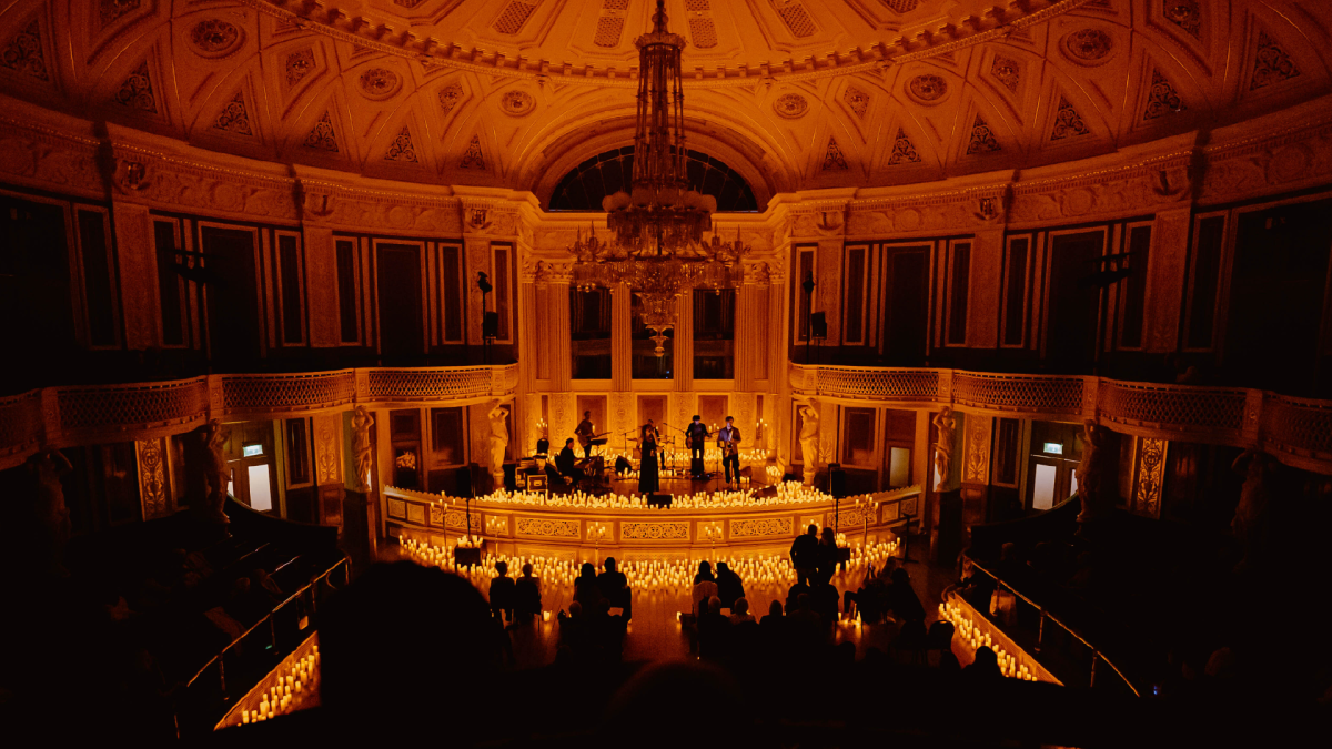Musicians on stage surrounded by hundreds of candles