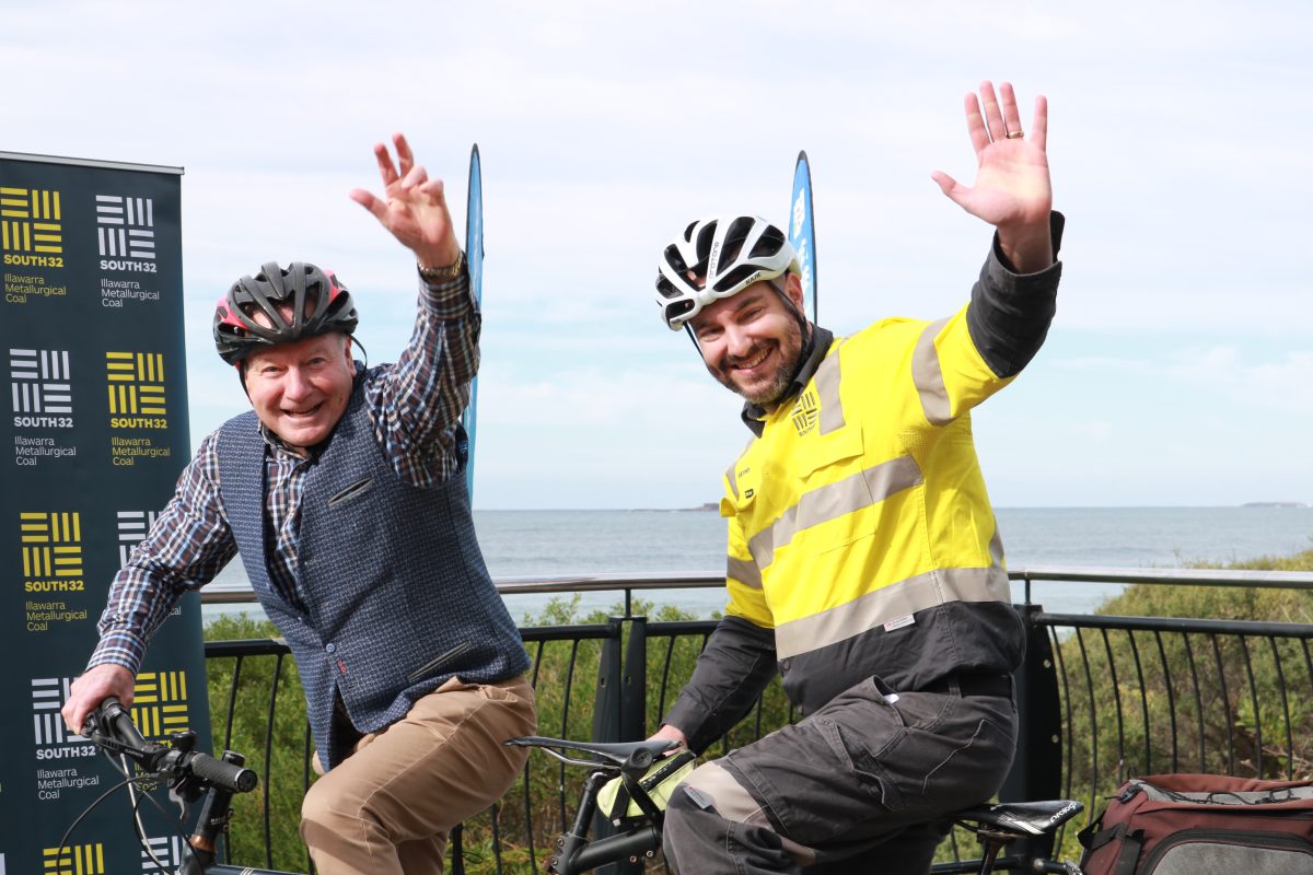 Gordon Bradbery and Antony Leone sitting on the tandem bike waving.