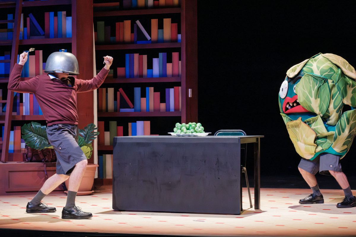 Production shot of Just Live on Stage at Merrigong showing a man with a pot on his head fighting an angry cabbage monster
