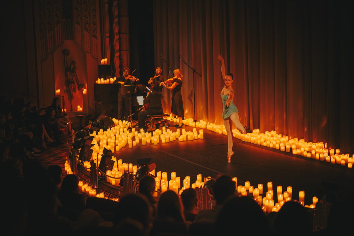 Classical musicians and a ballerina on a stage surrounded by hundreds of candles