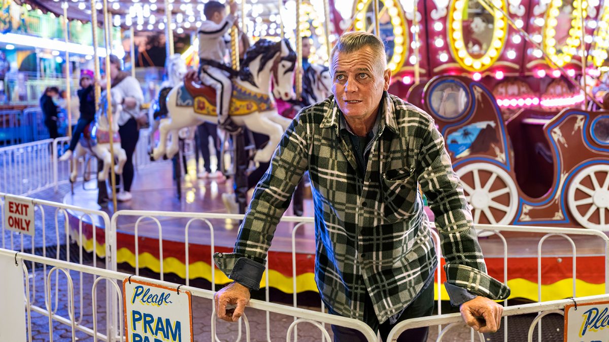 Man stands in front of a carnival ride at night