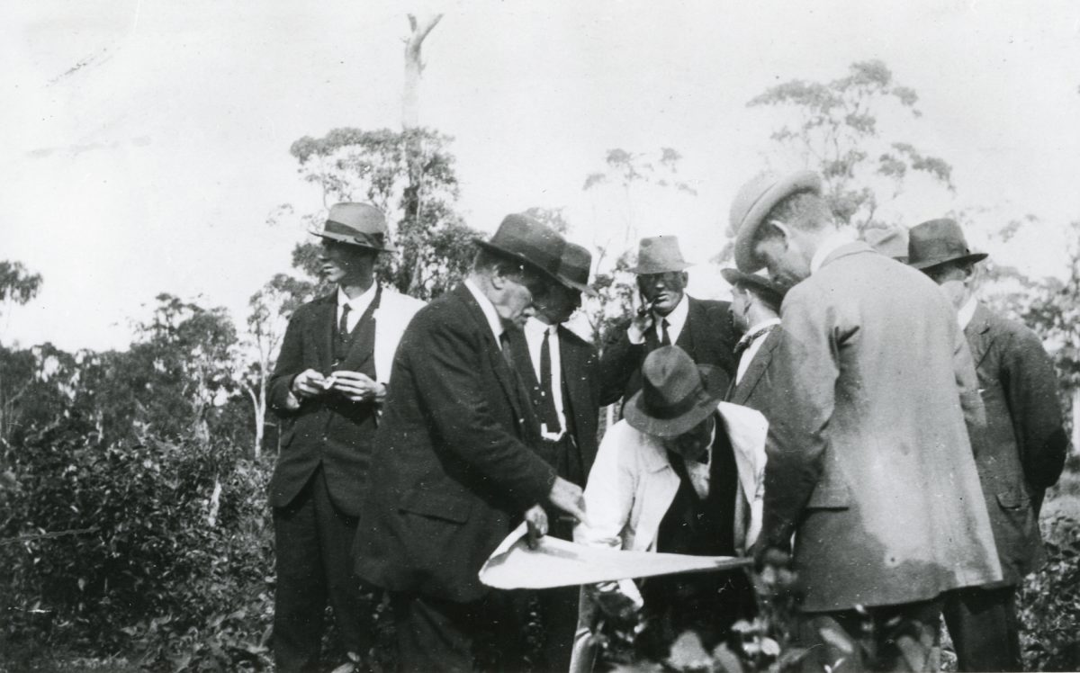 A group of men inspecting construction plans in 1922 