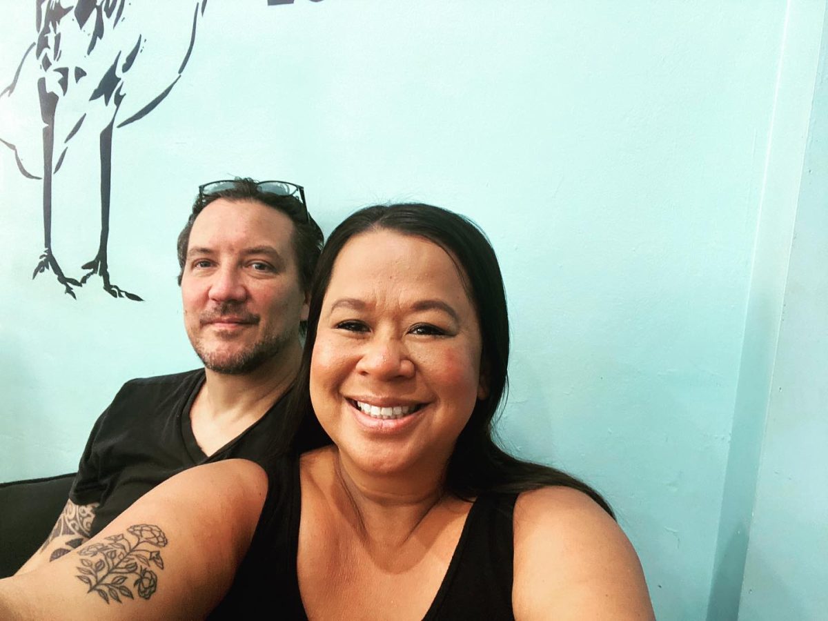 Chris and Alice from Blackbird Thirroul smile at the camera in front of a light blue wall