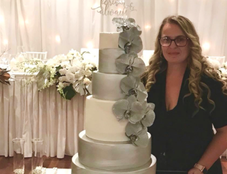 Kylie next to a wedding cake she made.