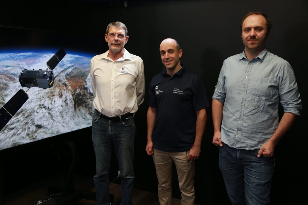Three men in front of projected image of Earth