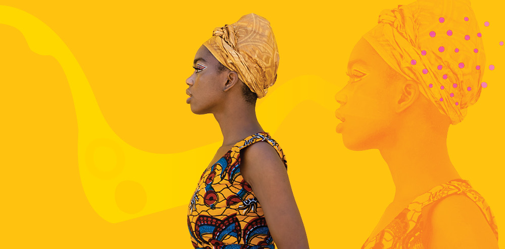 African woman standing in profile in front of a yellow backdrop. 