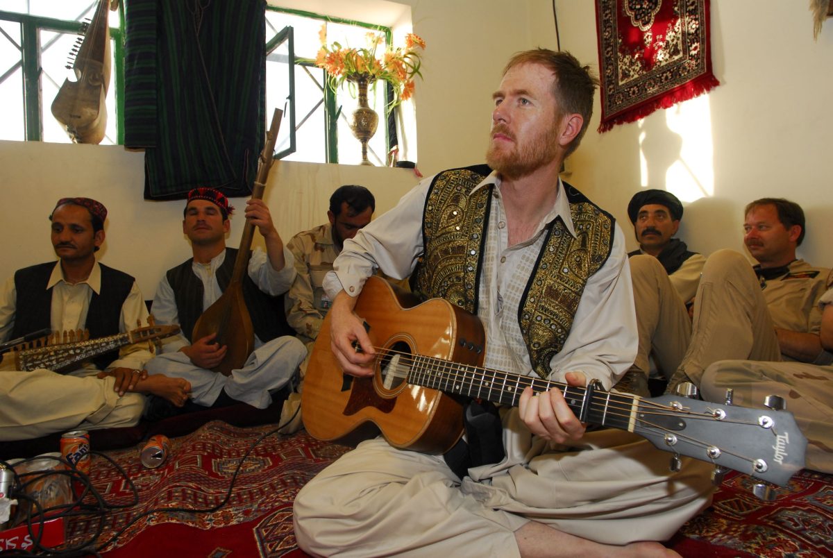 Fred Smith playing guitar to a group in Afghanistan.