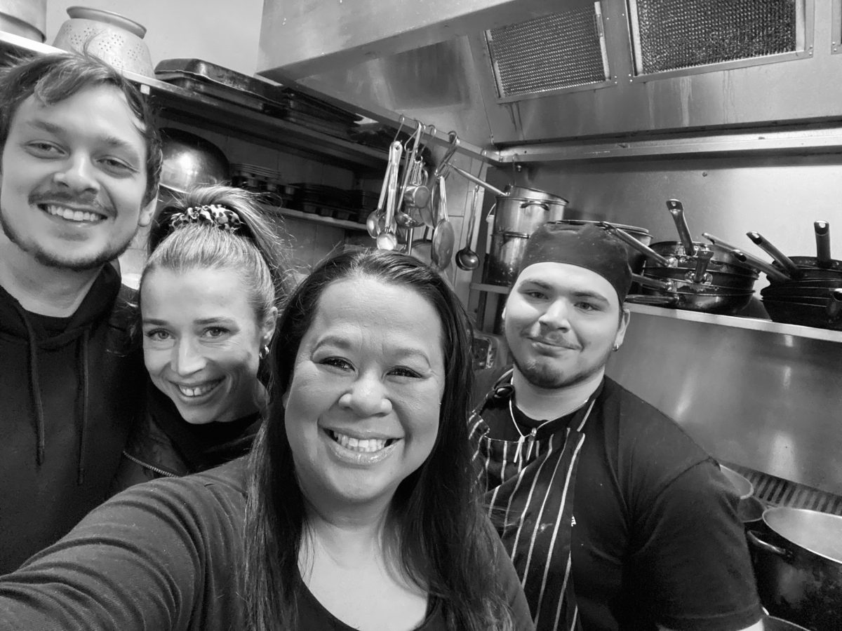 Four cafe staff members in a kitchen smiling