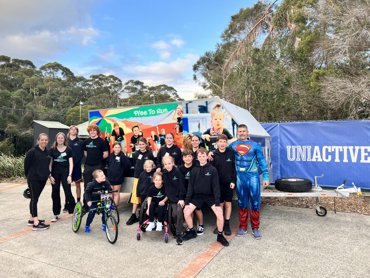 Kids, parents and volunteers from Frame Running Wollongong standing in front of their newly donated trailer.