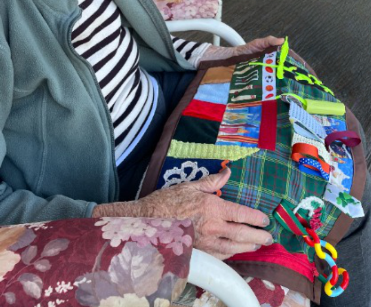 elderly hands play with a colourful fiddle mat