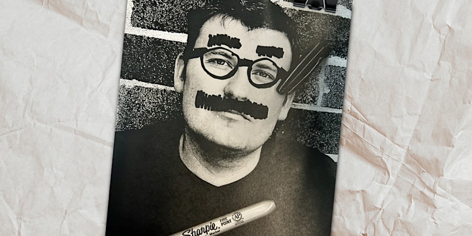Black and white picture of a man with a moustache and thick eyebrows drawn on with a Sharpie