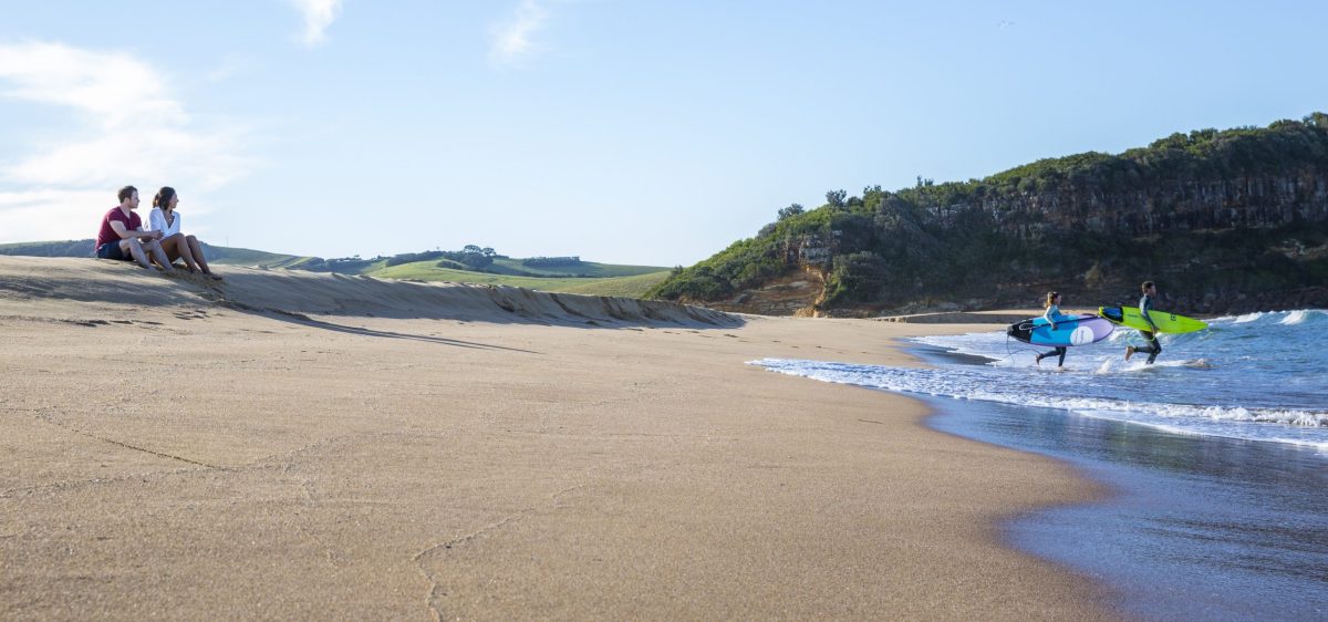 Couple heading into the surf at Werri Beach.