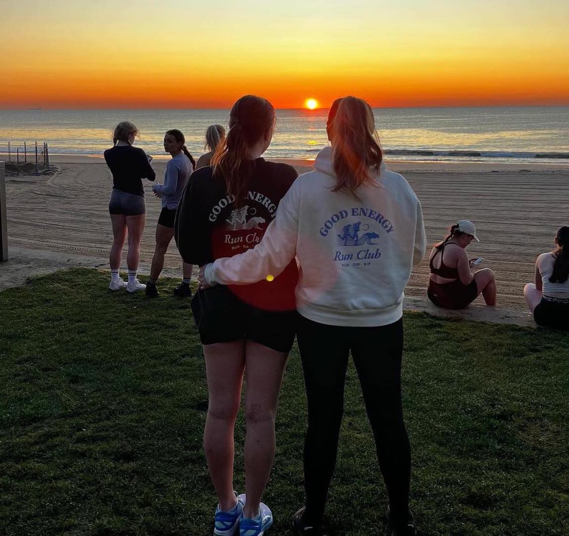 Women in the Good Energy Run Club watching a sunrise together at North Wollongong Beach