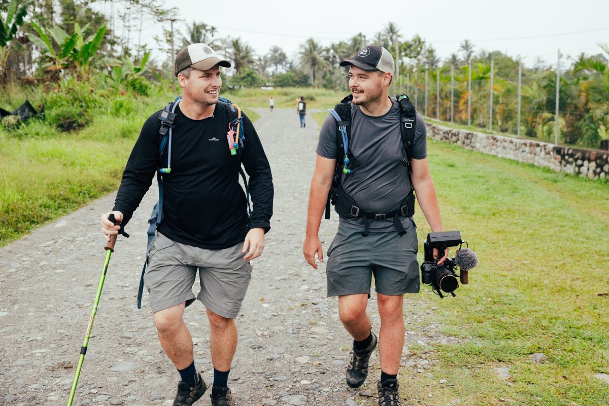 Lachlan Stevens and Mitchell McArdle carrying camera at end of Kokoda trail.