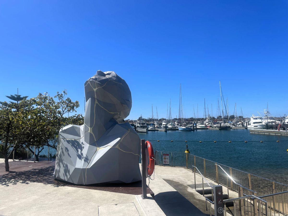 Sculpture of giant head leaning towards the sun, next to the Shell Cove marina. 