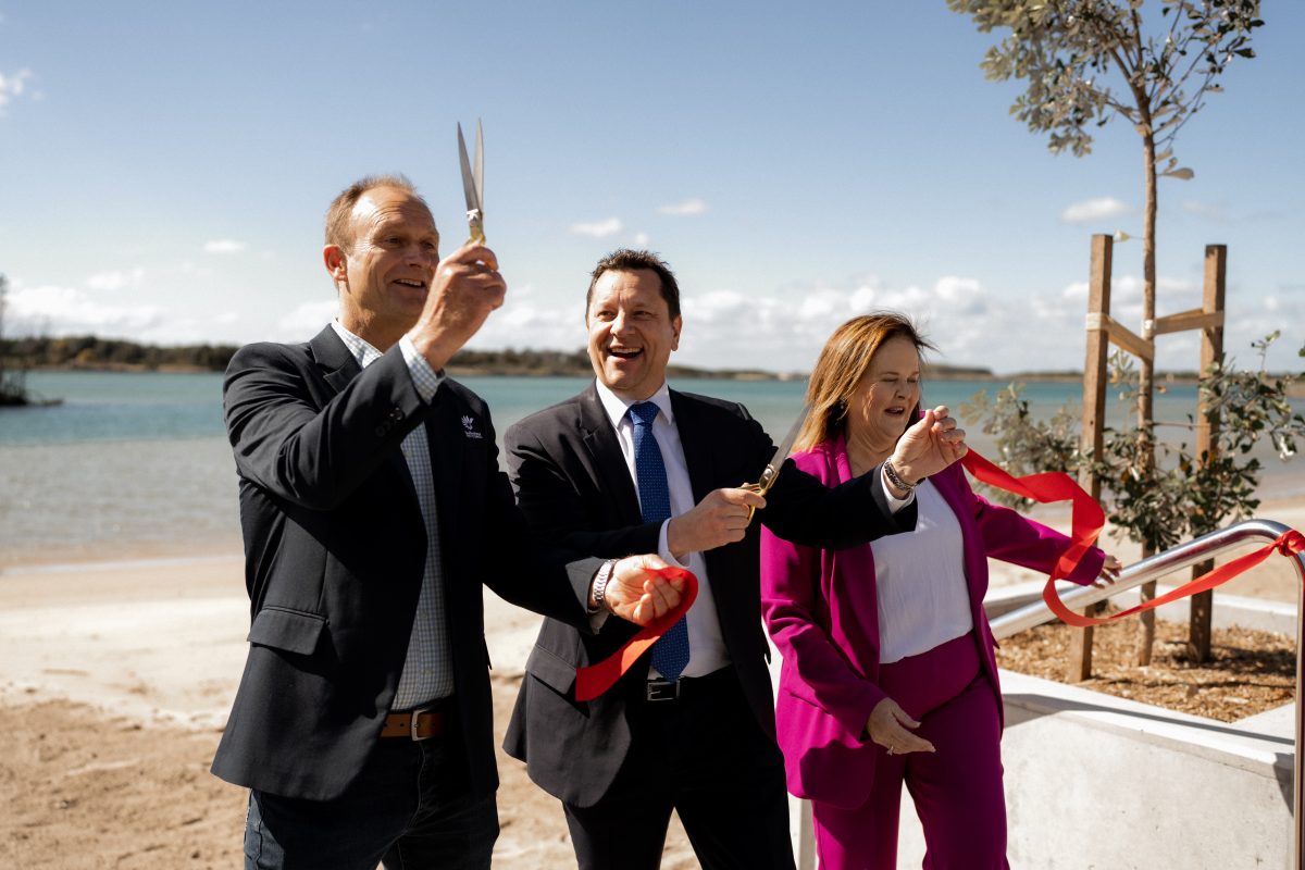 Two men and a woman perform a ribbon-cutting ceremony