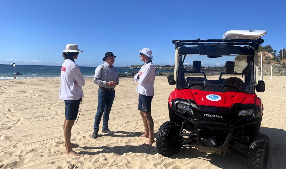 man speaking with two lifesavers on beach