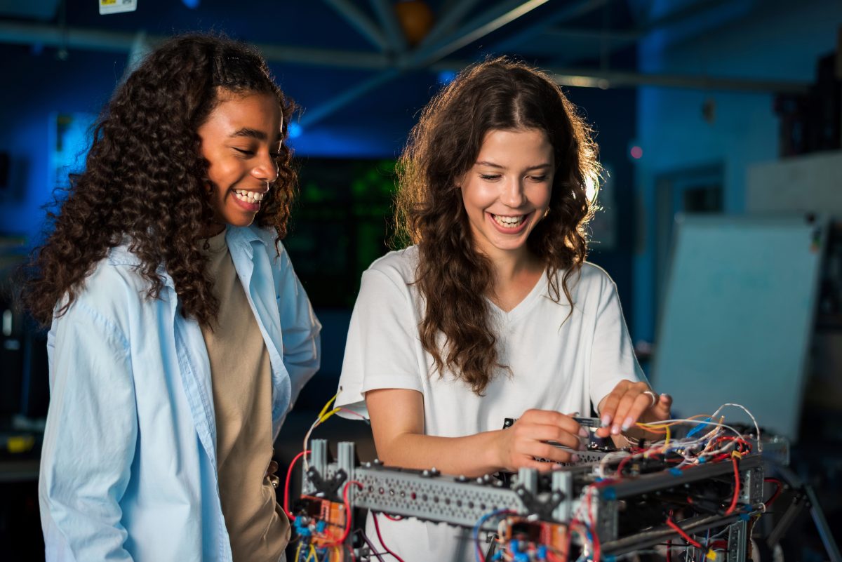 Two young women interact with robotics project