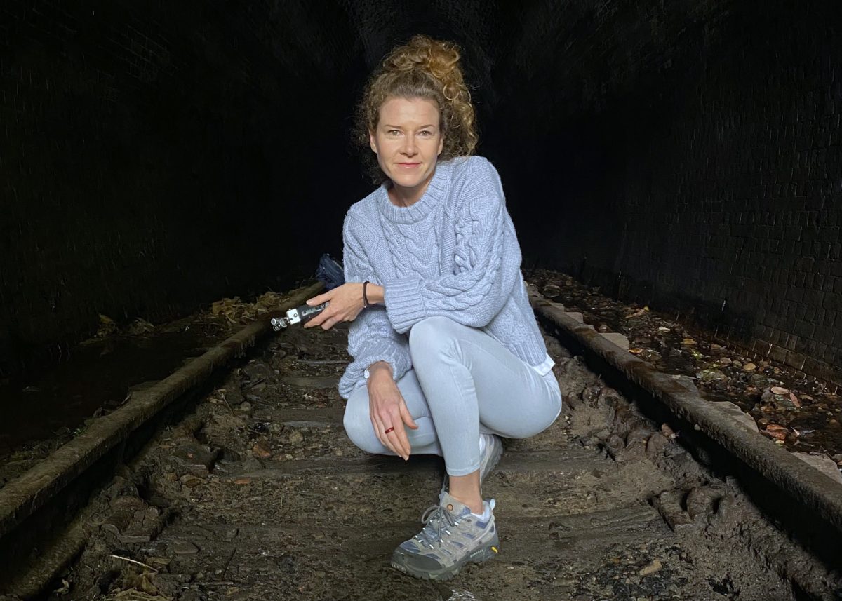 Actor, musician and TAFE NSW Wollongong graduate Mckenzi Scott crouches on the railways at the old Helensburgh rail tunnel
