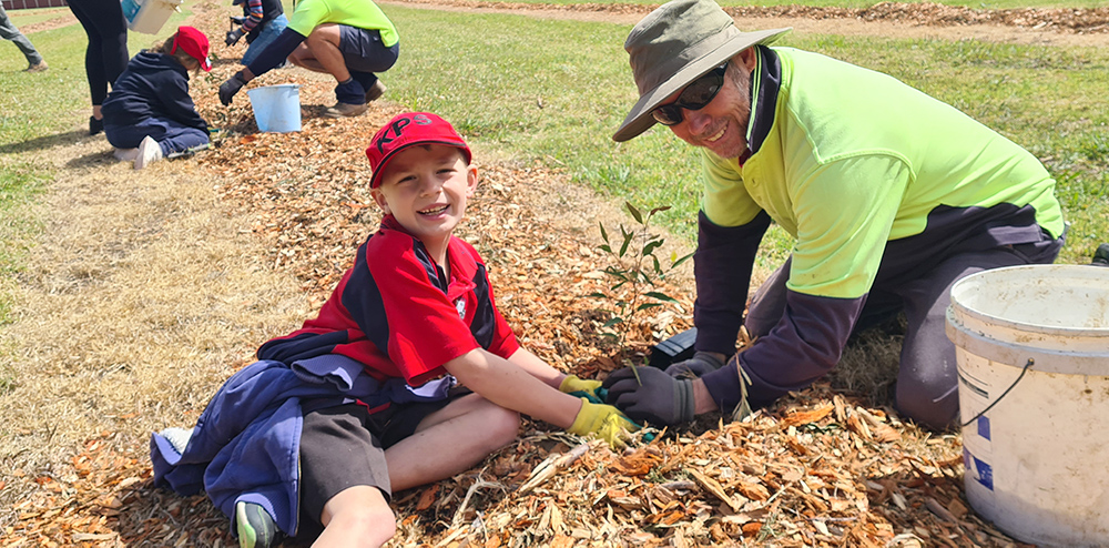  A child and worker from Wollongong Council planting a tree together. 