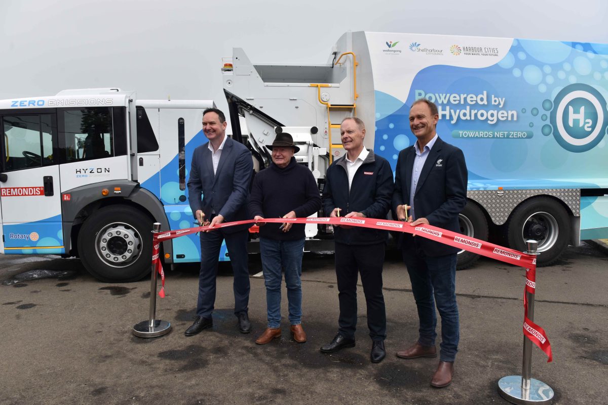 four people at ribbon-cutting ceremony for hydrogen-powered garbage truck