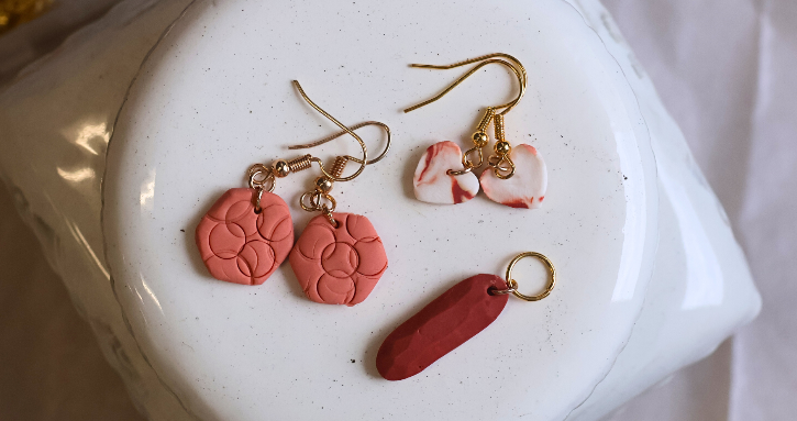 Several red and pink clay earrings on a white dish