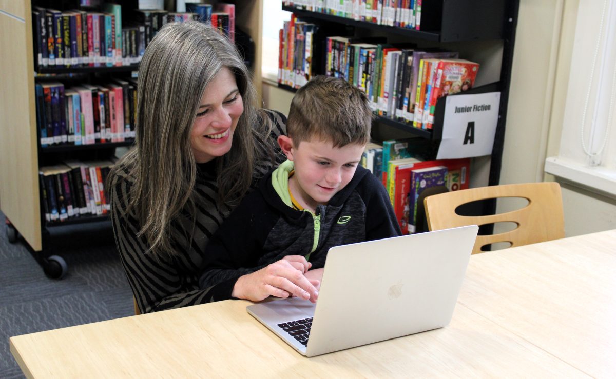 Erin Huckle from Chuckle Communications and one of her sons looking at a computer.