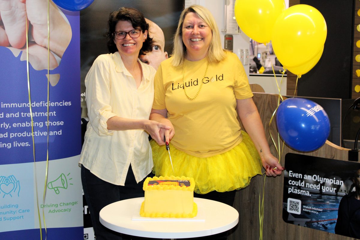 Susan Edwards and Lifeblood Wollongong worker cutting cake. 