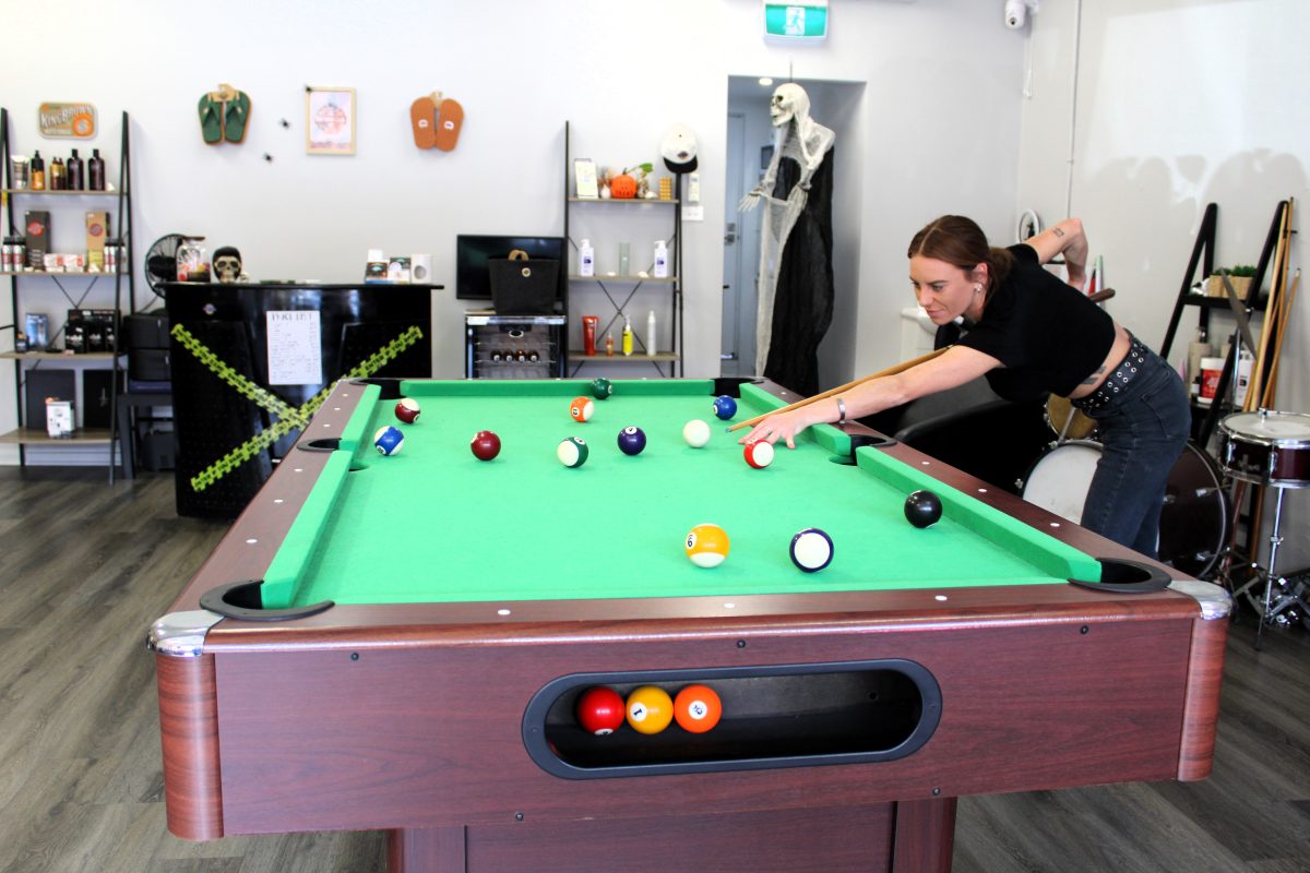 Shave Cave Owner Martelle Jackson playing pool. 