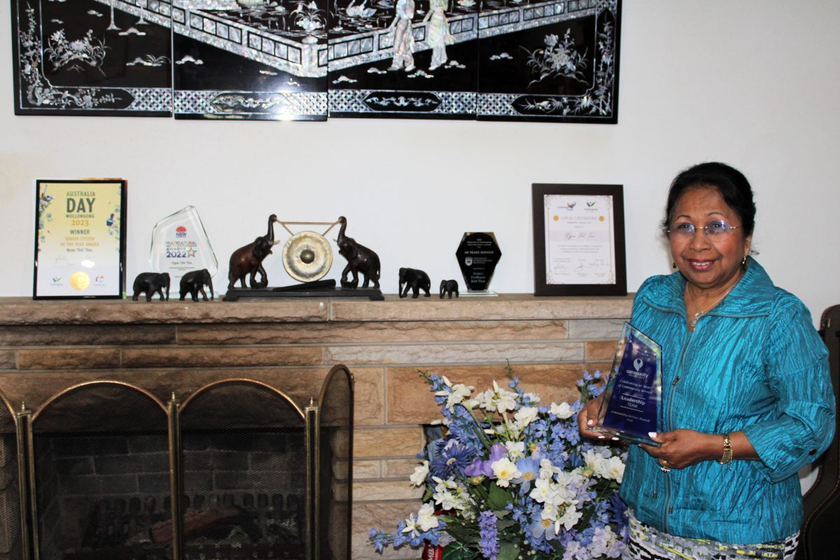 Nyan Thit Tieu holding community service award with some other awards.