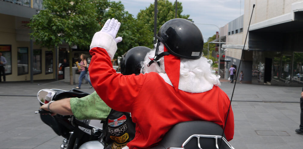 Shot from behind of Santa riding tandem on a motorcycle and waving