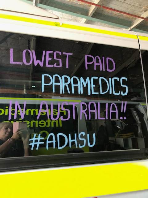 Writing on the window of an ambulance reads 'lowest paid paramedics in australia'