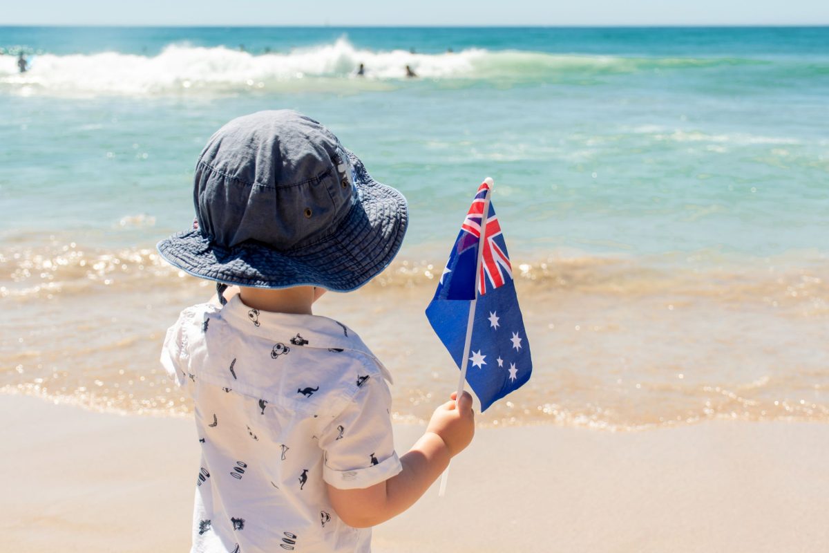 Boy with Australian flag at water's edge.