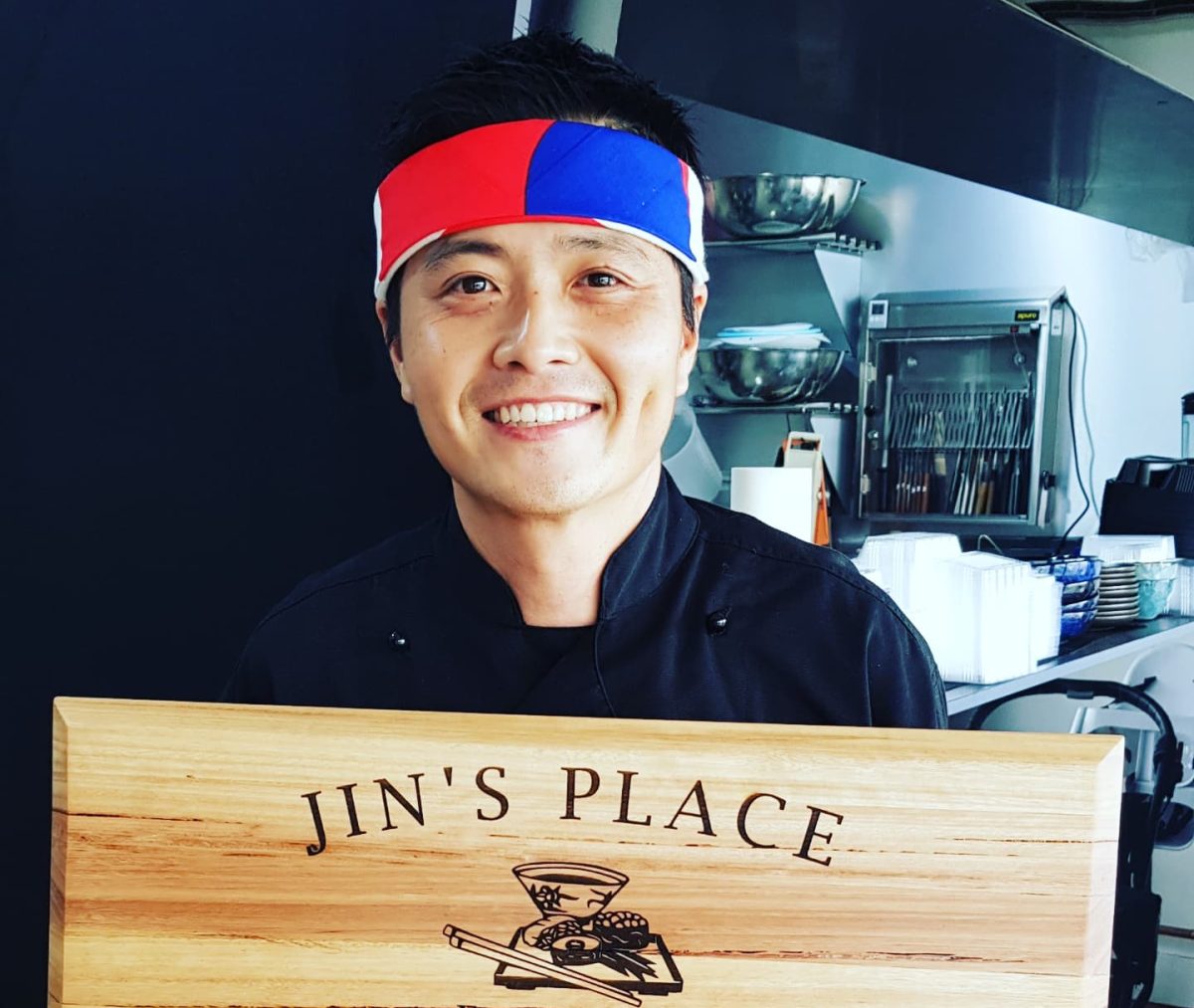 Jin Kim holding a Jin's Place sign