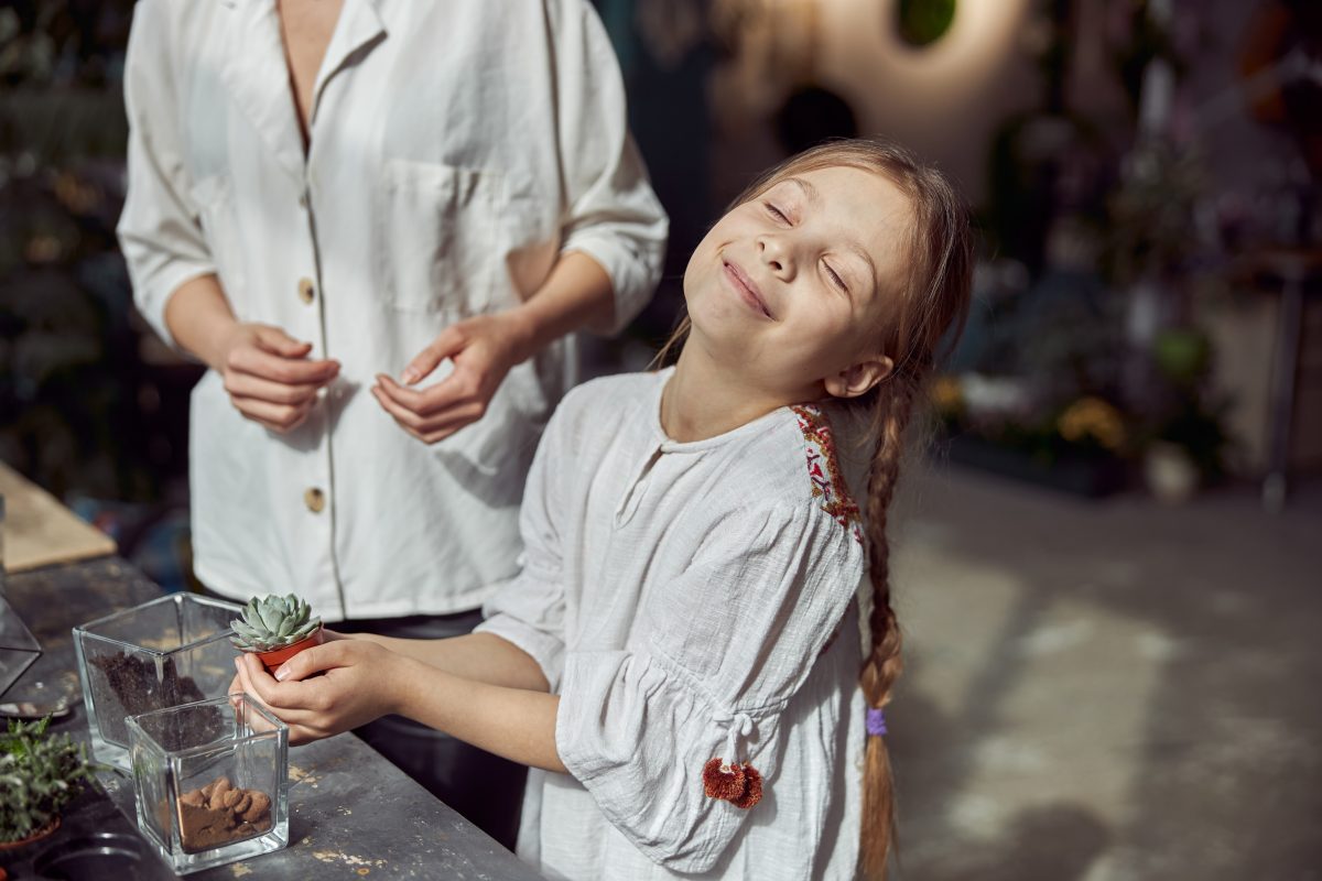 A florist is working with her young daughter and making a terrarium