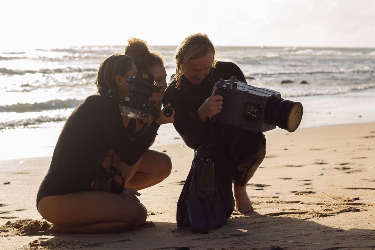 Three people crowd around a film camera on Coledale Beach