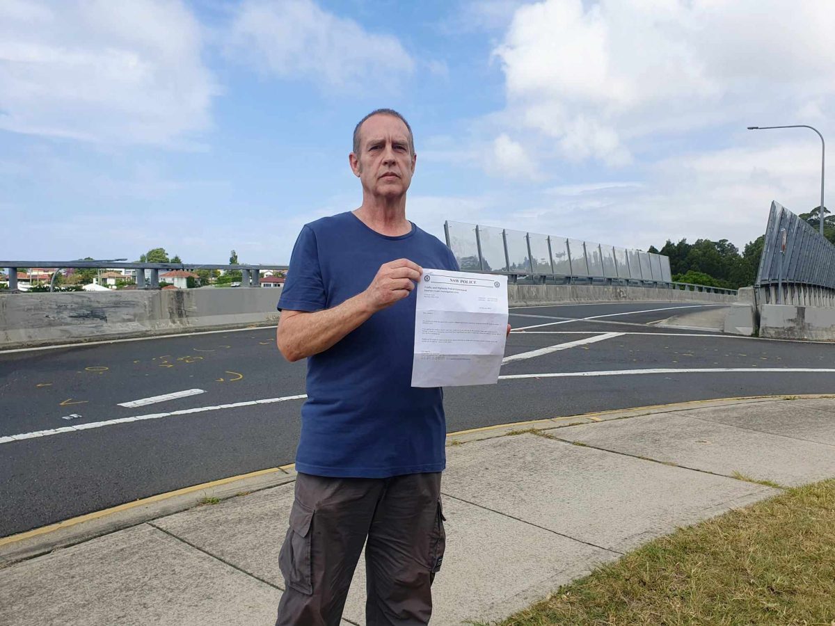 man standing on footpath and holding a letter