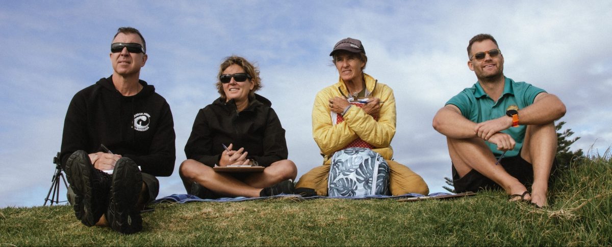 Four people watching students surf.