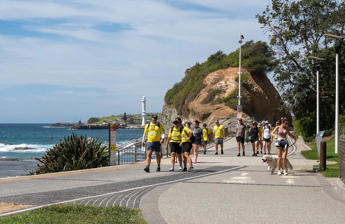 People in yellow T-shirts walking along a coast for the Great Illawarra Walk