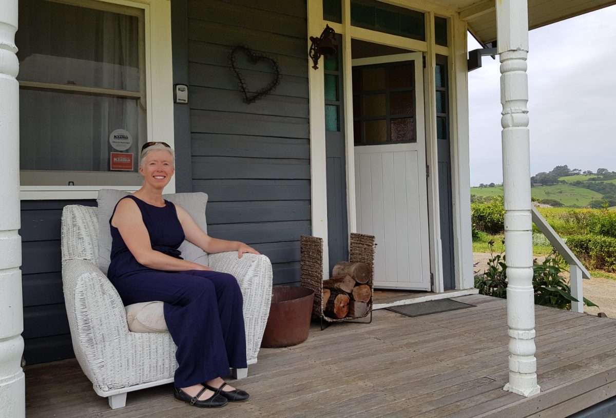 woman sitting on front verandah chair of historic country house