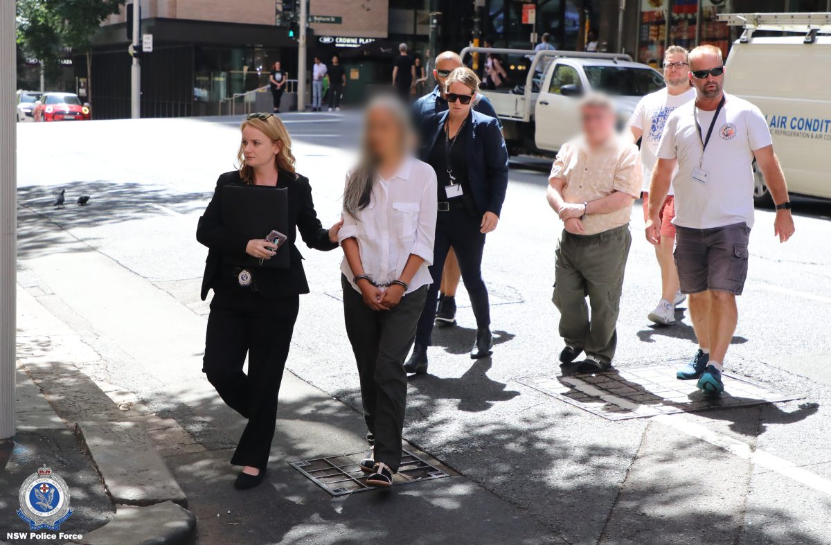 Police with two handcuffed people whose faces are blurred