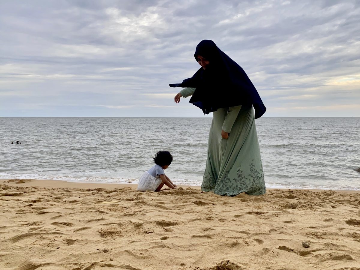 Muslim woman and her daughter on the beach